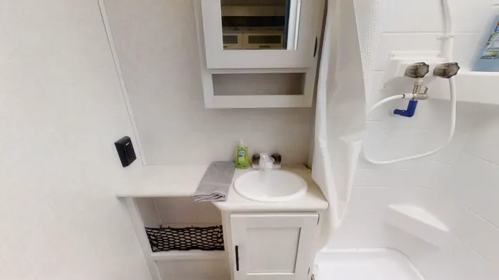 Inside an RV rental bathroom, featuring a compact sink, vanity, mirrored cabinet, and shower with curtain.. Forest River R-Pod 2022
