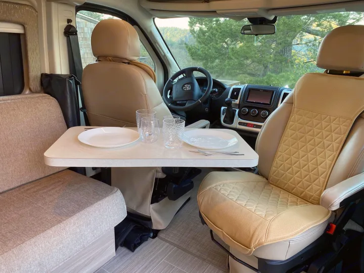 Inside a cozy rv rental: front seats swivel to a dining table set for two, perfect for comfortable travel.. Thor Motor Coach Scope 2022