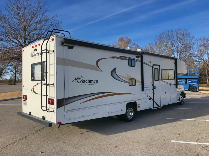 This white Coachmen Freelander RV rental, a recreational vehicle, is parked in an asphalt lot under a clear sky.. Coachmen Freelander 2014
