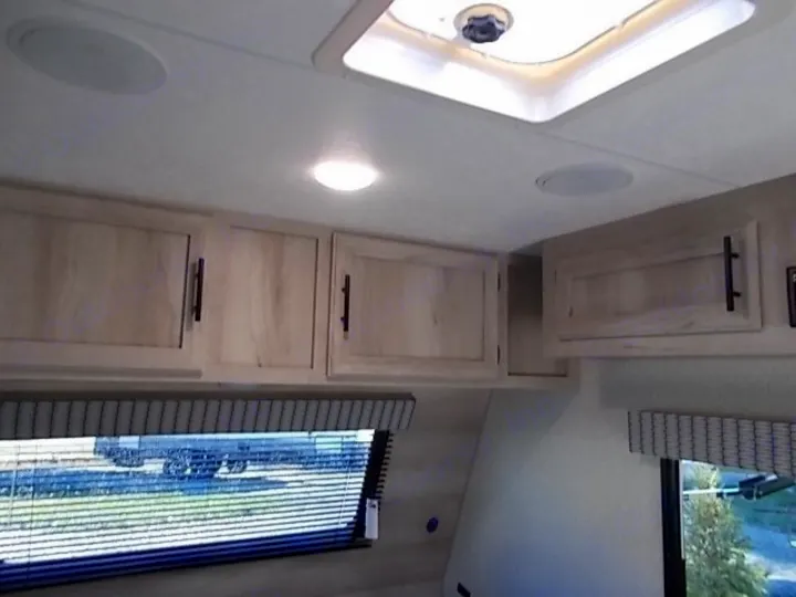 Inside your RV rental: bright, clean overhead cabinets, ceiling speakers, and a skylight creating a comfortable living space.. Sportsmen Classic 2022