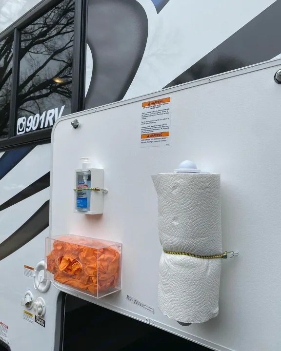 Practical RV rental exterior setup: hand sanitizer, gloves, and paper towels organized on the side panel for convenience and safety.. Thor Magnitude 2022