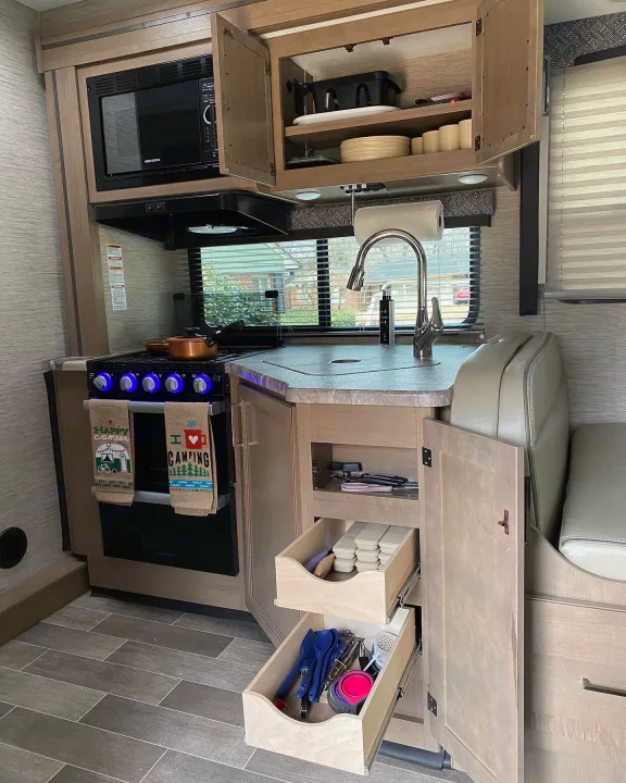 Explore this well-equipped RV rental kitchen: microwave, stove, sink, cabinets, and dining area. Perfect for your next camping trip.. Thor Magnitude 2022