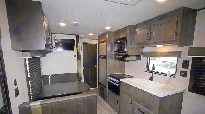 Modern RV rental interior with a full kitchen, dinette booth, TV, and overhead cabinets, offering comfort for road trips.. Jayco Jay Flight 2022