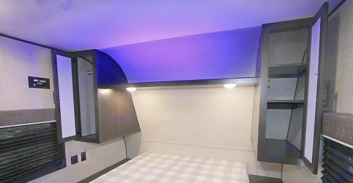Cozy RV rental bedroom featuring a comfortable bed, smart overhead storage, and stylish purple accent lighting.. Jayco Jay Flight 2022