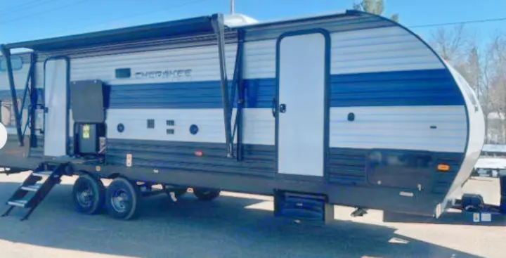 Modern blue and grey Cherokee travel trailer, ideal for an rv rental. Shown outdoors with awning extended and stairs deployed.. Forest River Cherokee 2021