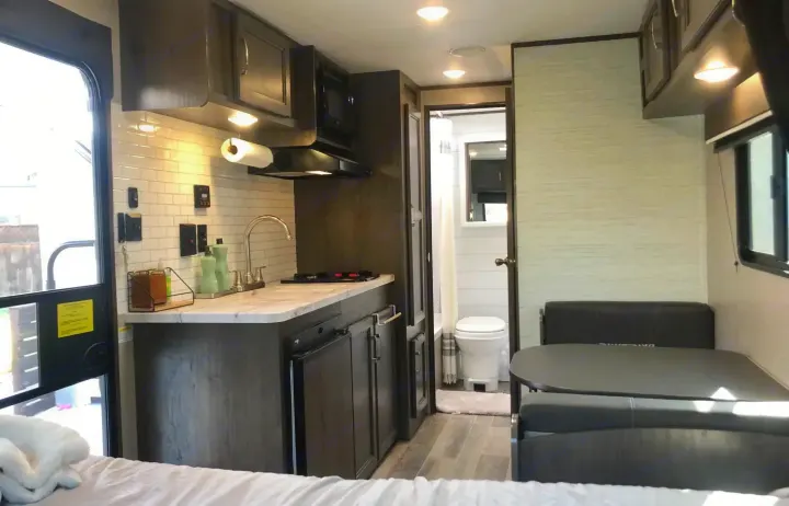 RV rental interior: A modern kitchen with white tile backsplash, an accessible bathroom, and a dinette area with seating.. Jayco Jay Flight 2021