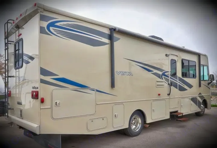 Spacious beige RV rental, a Vista motorhome with blue decals, side entry, and rear ladder for your next adventure.. Winnebago Vista 2018