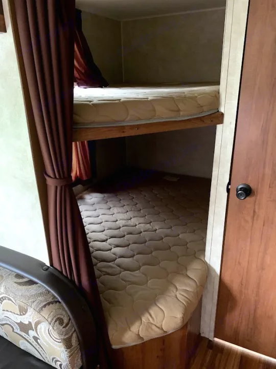 Inside an RV rental: two comfy bunk beds with mattresses & privacy curtains. Ideal for families.. Gulf Stream Amerilite 2015