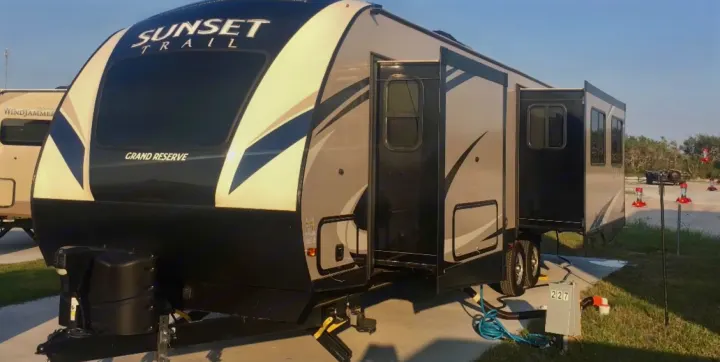 This Sunset Trail Grand Reserve travel trailer rv rental is set up at a campsite with hookups, ready for adventure.. Crossroads Sunset Trail Reserve 2018