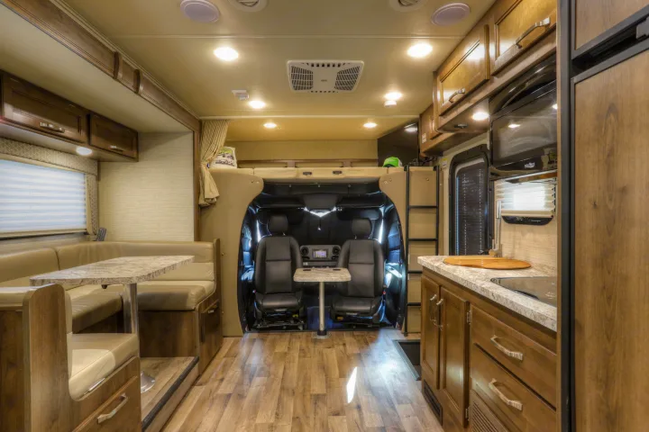 Spacious RV rental interior with dining booth, full kitchen, and front cab area featuring an overhead bunk bed.. Jayco Melbourne 2020