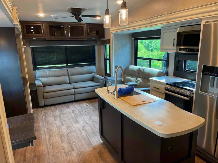 Modern RV rental interior with spacious living area, kitchen island, and comfortable gray recliners.. Jayco Eagle 2021