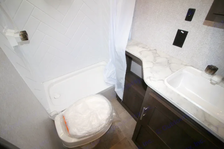 Clean RV rental bathroom featuring a shower, wrapped toilet, and vanity with sink. Ideal for travel trailer trips.. Dutchmen Coleman 2022