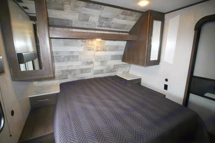Compact RV rental bedroom with a comfy bed, overhead storage, and stylish wood-paneled wall for travel comfort.. Dutchmen Coleman 2022