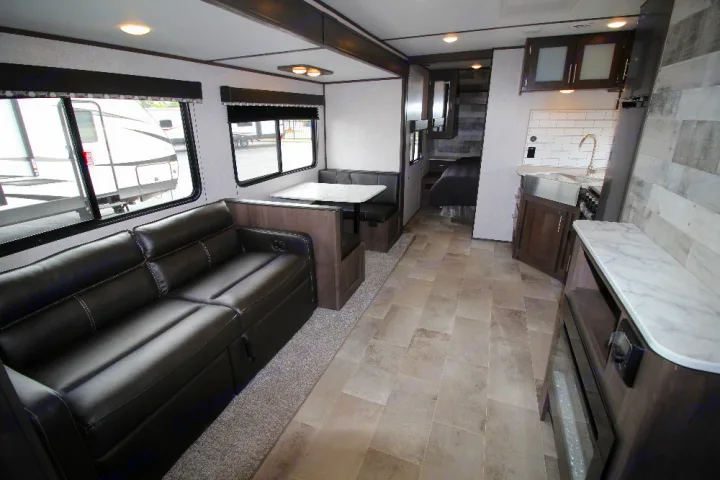 Spacious rv rental interior featuring a comfortable living area, kitchen, dining booth, and glimpsed bedroom.. Dutchmen Coleman 2022