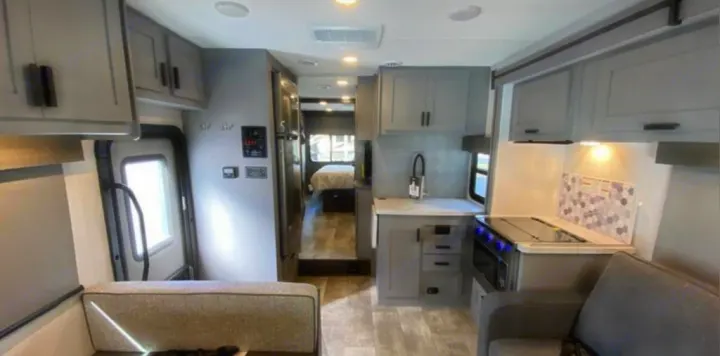 Modern RV rental interior: a clean, grey space featuring a kitchen, living area sofa, and hallway to the bedroom.. Forest River Solera 2022