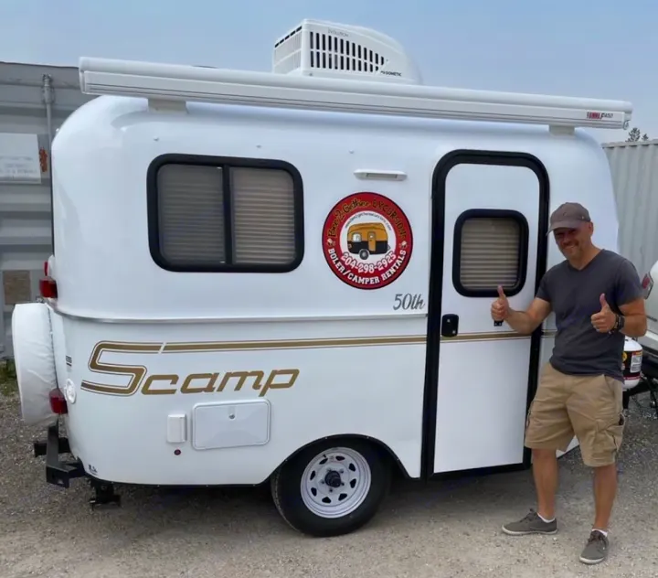 Man gives thumbs up next to a white Scamp travel trailer, available for RV rental. See Bee-2-Gather Excursions' cozy camper!. Scamp Scamp 2021