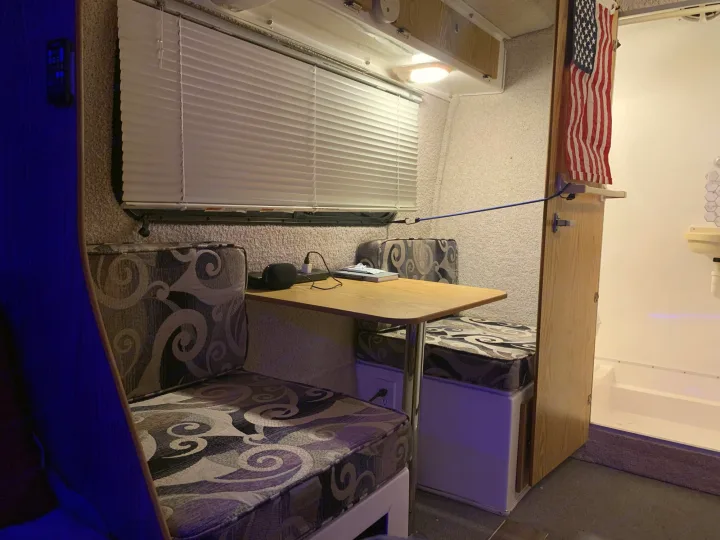 Cozy RV rental interior showing a dinette with patterned cushions, table, and window. An American flag is visible.. Casita 17' Spirit Deluxe 2010