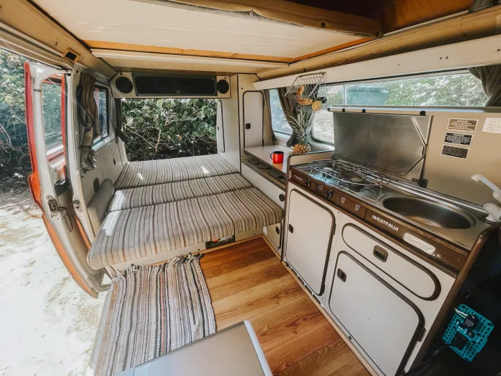 Interior view of a Westfalia RV rental camper van. Includes a bed, kitchen, and small dining area. Ideal for travel.. Volkswagen Westfalia 1983
