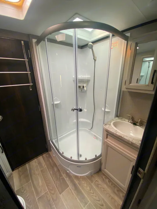 RV rental bathroom with compact corner shower, vanity sink, and skylight. Ideal for travel trailer adventures.. Jayco Jay Feather 2021