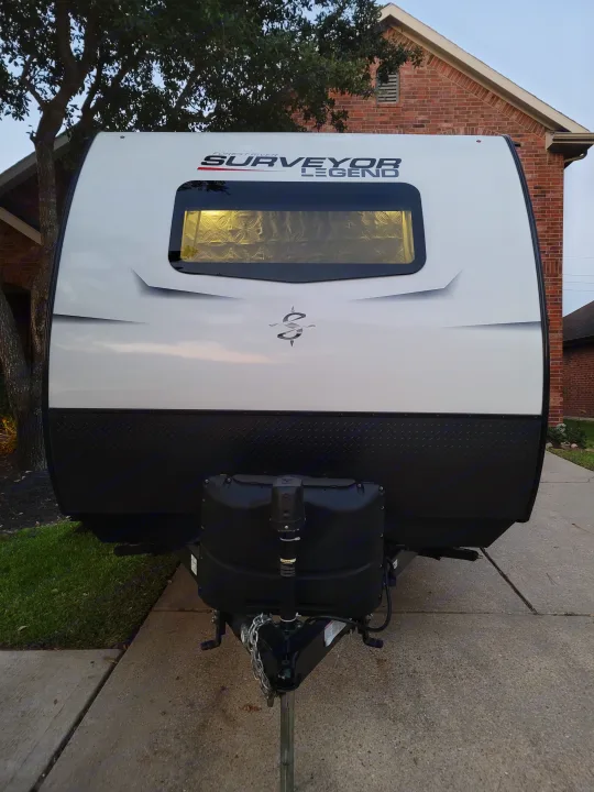 Front of a white Forest River Surveyor Legend RV, featuring black diamond plate & propane tanks, ready for an rv rental adventure.. Forest River Surveyor 2021
