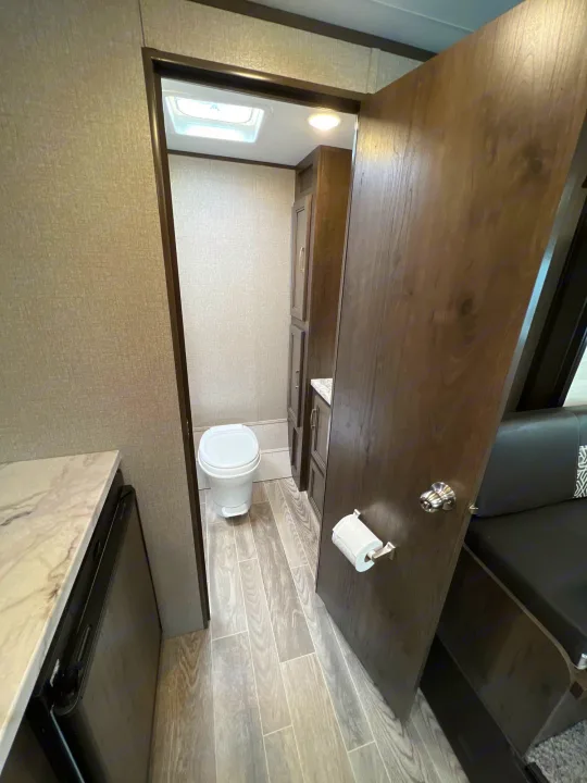 This RV rental showcases a compact bathroom with toilet, visible through an open door. Countertop & seating also seen.. Jayco Jay Flight SLX Baja Edition 2021