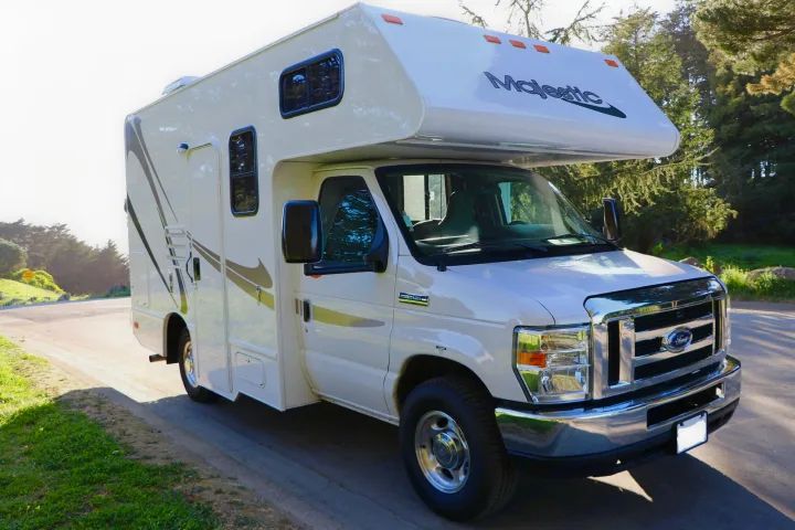 This white Ford Majestic Class C rv rental is parked on a sunlit road, ready for outdoor adventures.. Thor Majestic 2018