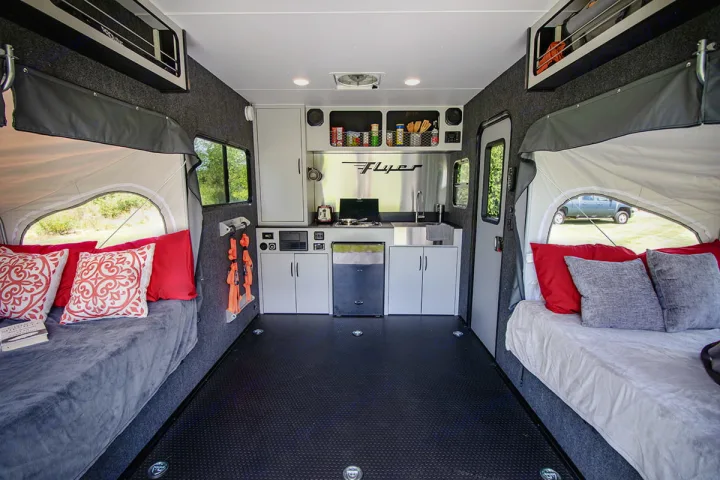 This RV rental interior showcases a compact kitchen with a fridge, sink, and stovetop, plus two comfy expandable beds. Great for road trips!. InTech RV Flyer Discover 2021