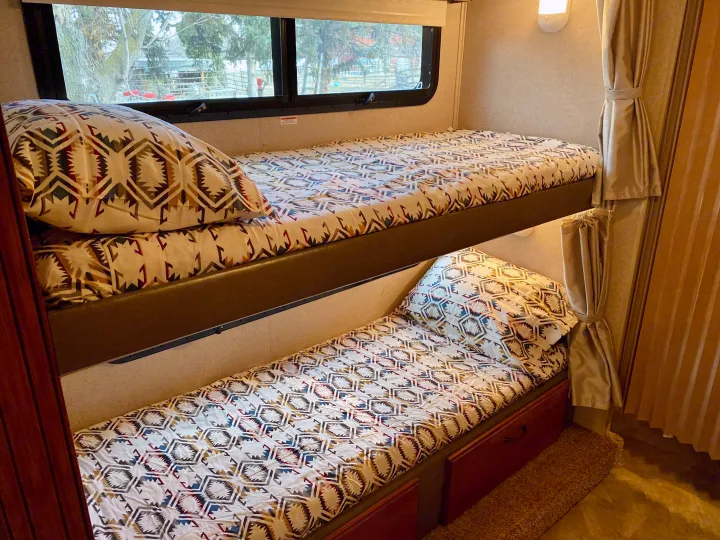 RV rental bunk beds, featuring cozy southwestern-style geometric bedding. A compact and comfortable sleeping solution for your trip.. Jayco Redhawk 2016