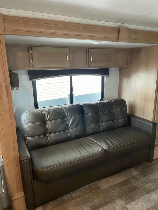 Comfortable RV rental interior: dark leather-look sofa, overhead cabinets, and a window for scenic views.. Winnebago Minnie 2020
