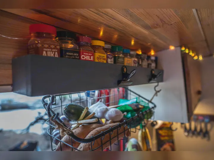 RV rental kitchen: Organized spice shelf with Trader Joe's jars & hanging produce basket. Compact setup.. Dodge promaster 3500 2018