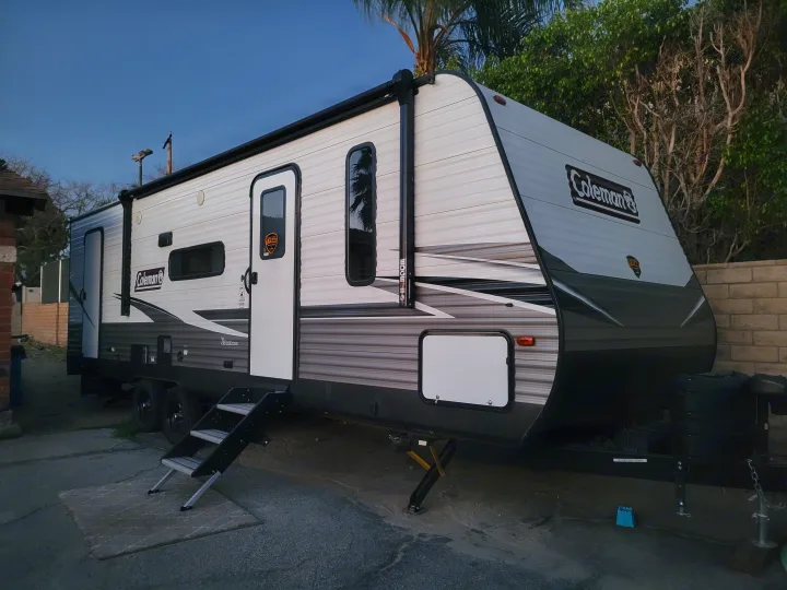 Ready for an outdoor escape? This spacious white & gray Coleman RV rental is parked with steps and stabilizers deployed.. Coleman 263 BH Lantern Edition 2021