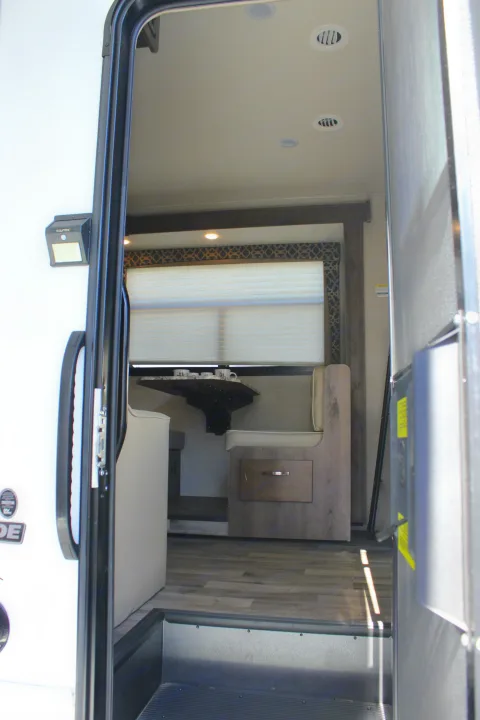 View inside an rv rental, showing a dinette, window, and sleeping area with modern wood accents.. Jayco Redhawk 2020
