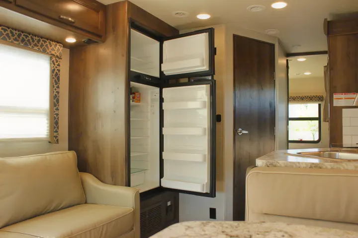 Step into this RV rental! Features include an open refrigerator, a cozy left-side couch, and a compact kitchen.. Jayco Redhawk 2020