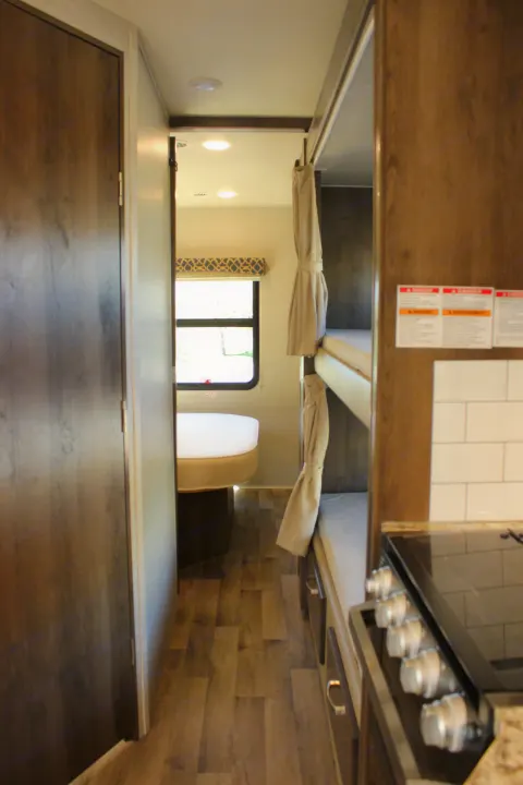 Spacious RV rental interior featuring a modern kitchen, wood flooring, and comfortable dining area.. Jayco Redhawk 2020