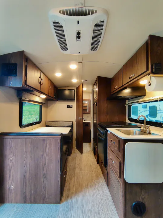 Spacious RV rental interior with kitchen, dinette, bathroom, and overhead AC unit for comfortable travel.. Forest River Geo Pro 2018