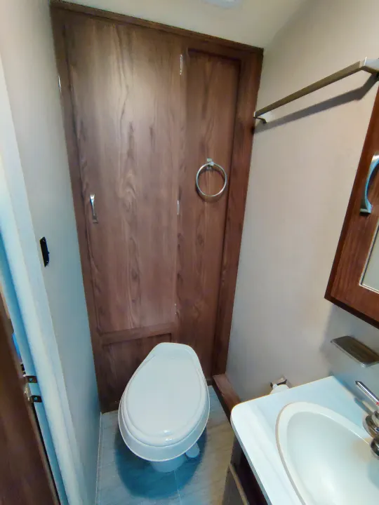 Inside an RV rental: a compact bathroom features a toilet, sink, and wooden storage, optimized for small spaces.. Forest River Geo Pro 2018
