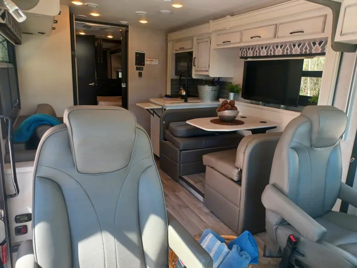 Modern RV rental interior showing front seats, dinette, and kitchen space. Perfect for comfortable travel.. ENTEGRA VISION A27 2022