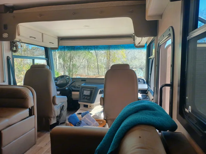 Comfortable RV rental interior with cockpit, plush seating, and scenic outdoor view. Ready for your next adventure.. ENTEGRA VISION A27 2022