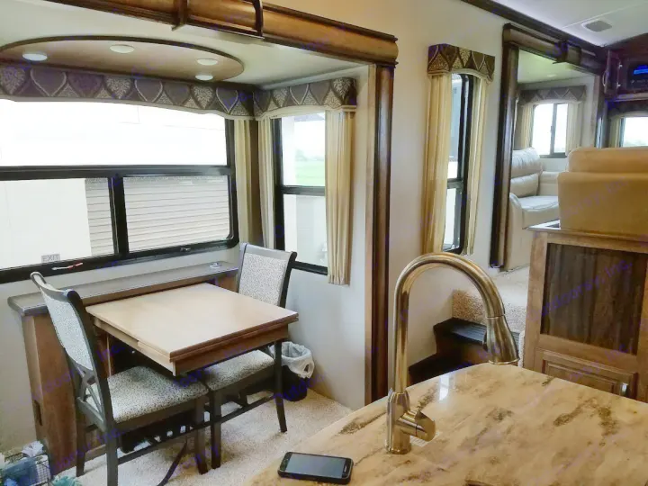 Spacious RV rental interior with a cozy dining area, bright windows, and a well-equipped kitchen. Ideal for comfortable travel.. Keystone Montana 2017