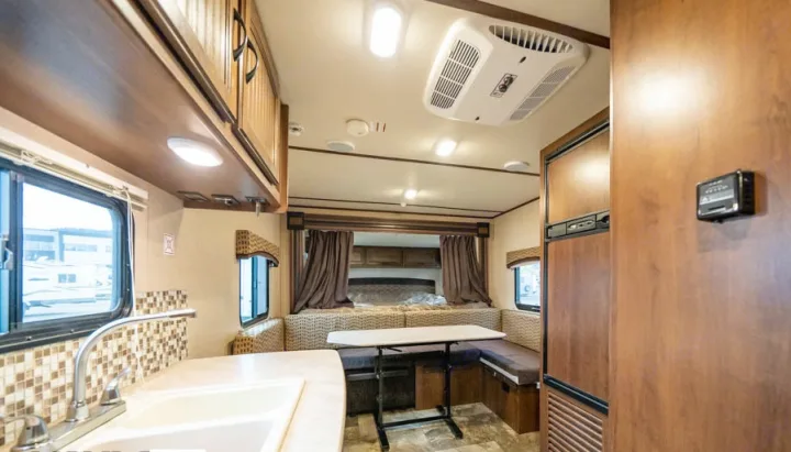 RV rental interior: kitchen with sink, cozy dining booth, and a bedroom with curtains in this compact, well-lit living space.. Jayco Jay Feather Ultra Lite 2015