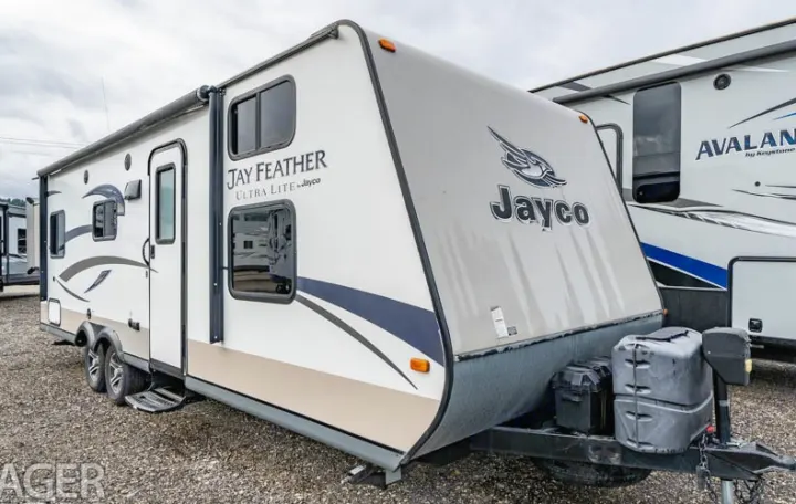 A white and tan Jayco Jay Feather travel trailer parked outdoors, an excellent RV rental choice.. Jayco Jay Feather Ultra Lite 2015