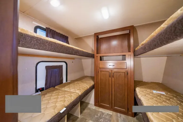 RV rental interior showcasing multiple bunk beds and a central storage unit, optimizing sleeping space for travelers.. Jayco Jay Feather Ultra Lite 2015