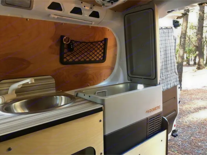 This RV rental offers a well-equipped mobile kitchen with a sink, faucet, and a Dometic cooler, perfect for nature getaways.. Cascade Campers Ram Promaster City 2020