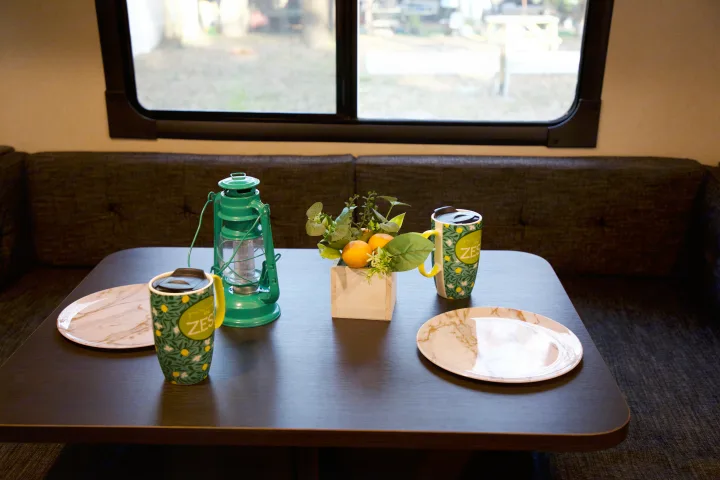 Inviting RV rental dining space: table with "ZES" mugs, marble plates, green lantern, & oranges.. Forest River Salem 2018