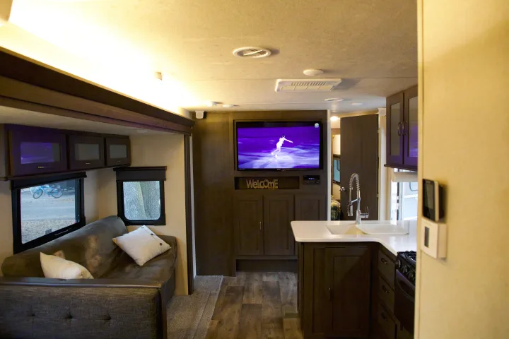 Well-lit RV rental interior with a cozy sofa, entertainment center, and equipped kitchen.. Forest River Salem 2018
