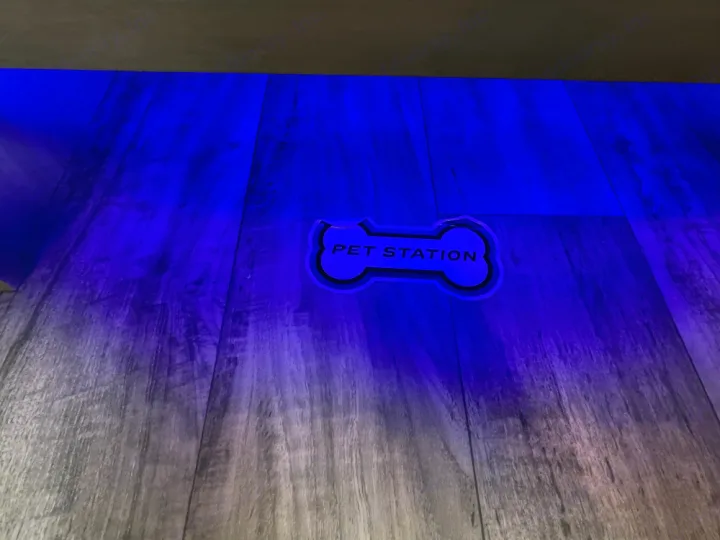 Blue ambient lighting illuminates a dark wood floor in an RV rental, featuring a bone-shaped "PET STATION" mat.. Crossroads Sunset trail 242HB 2022
