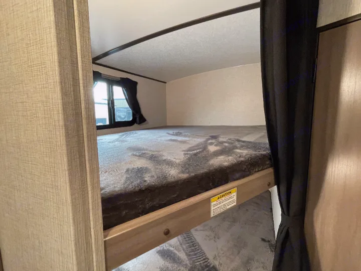 Inside an RV rental: view of bunk beds with a soft mattress and window, offering a cozy sleeping space for your next trip.. Crossroads Sunset trail 242HB 2022