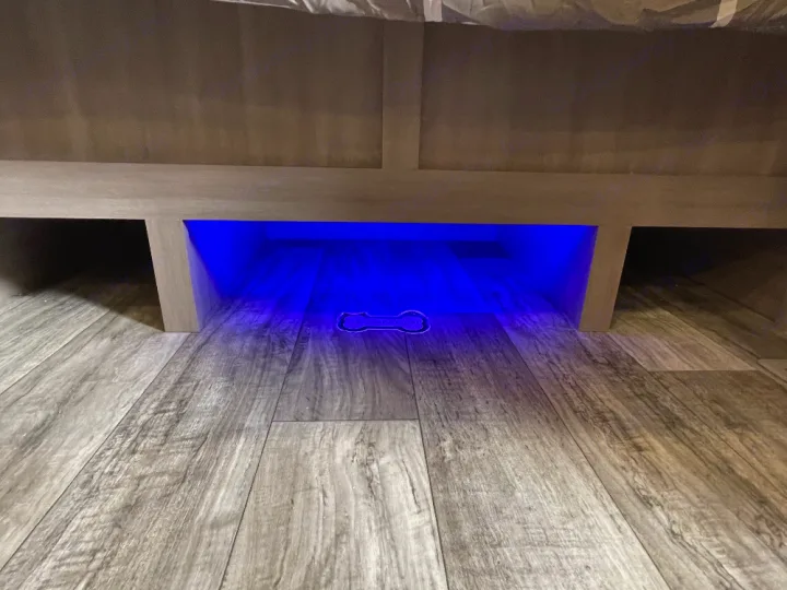 Cozy blue under-bed LED lighting illuminates a laminate floor in this modern RV rental, with a small object visible.. Crossroads Sunset trail 242HB 2022