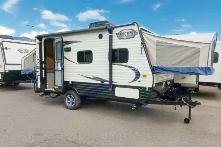 A white & black travel trailer RV, great for rv rental trips. Features a pop-out bed extension & open door.. Coachmen Viking 2018