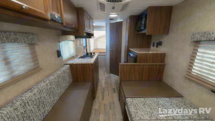 Interior of an RV rental showing the compact kitchen, comfortable dinette seating/beds, and wood-look flooring. Ready for adventure.. Coachmen Viking 2018